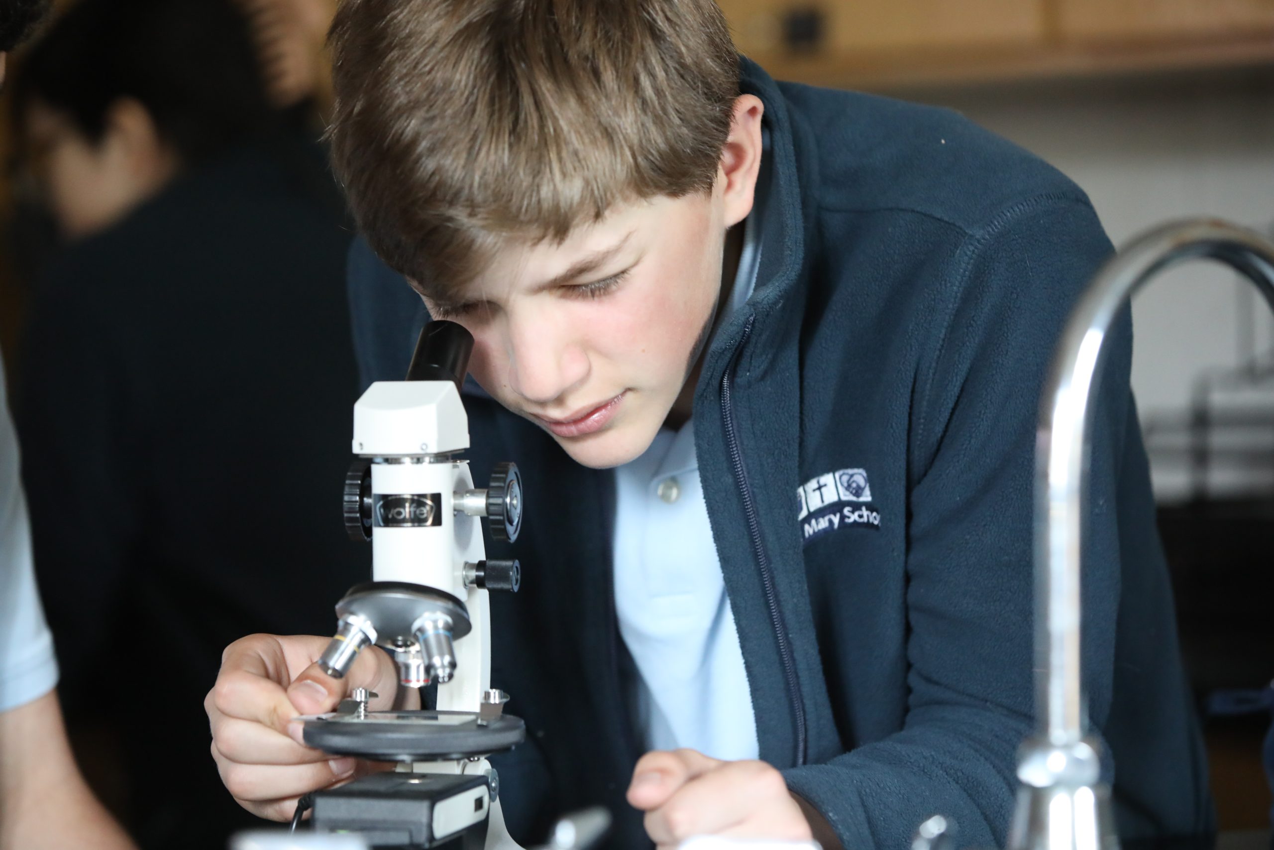 Middle School student in science lab using microscope