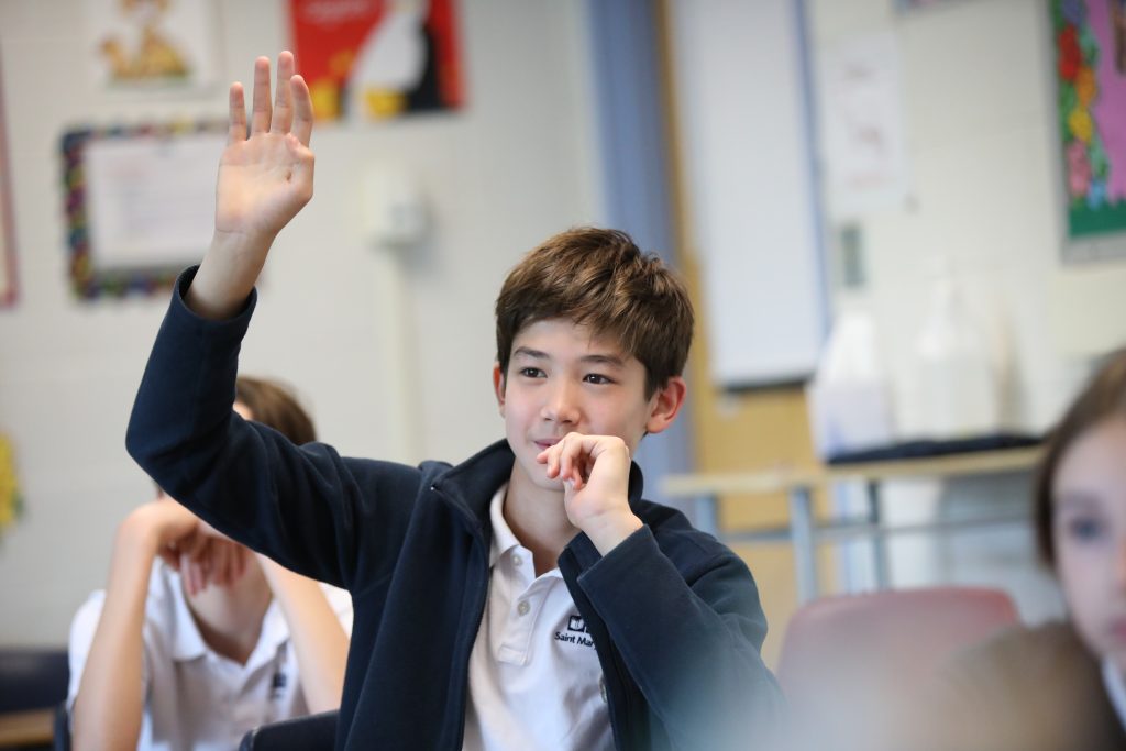 Middle School boy raising hand to answer question